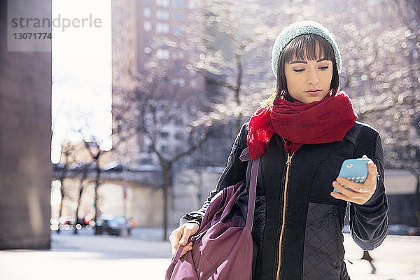 Frau benutzt Smartphone  während sie in der Stadt auf der Straße steht