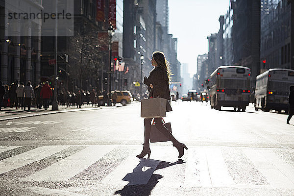 Seitenansicht einer Frau  die in der Stadt die Straße überquert