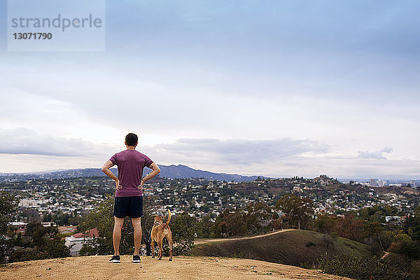 Rückansicht eines Athleten mit Hund auf dem Berg stehend