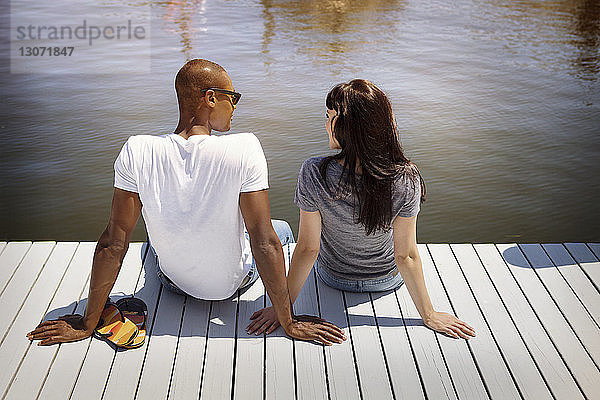 Rückansicht des auf dem Pier sitzenden Paares