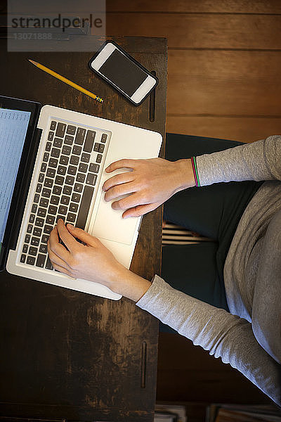 Hochwinkelansicht einer Frau  die einen Laptop-Computer benutzt  während sie am Tisch sitzt