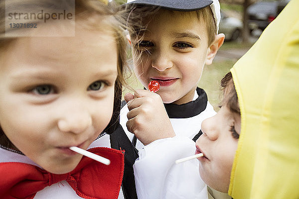 Nahaufnahme von glücklichen Kindern in Halloween-Kostümen  die Lollipops essen