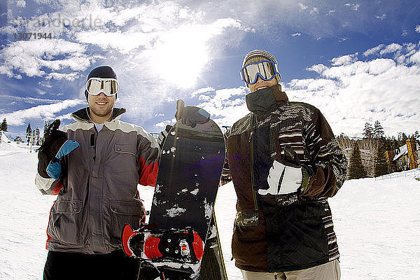 Porträt glücklicher Snowboarder vor bewölktem Himmel