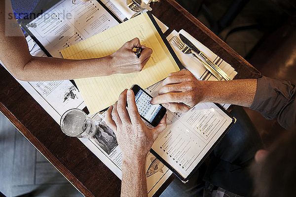 Draufsicht auf einen Mann  der ein Smartphone benutzt  während er mit seiner Freundin im Restaurant sitzt