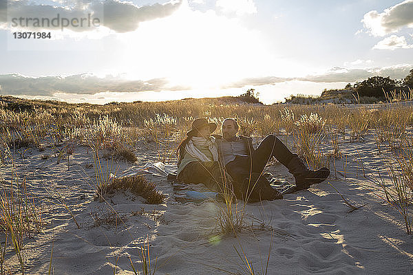 Ehepaar entspannt sich auf Sand gegen den Himmel