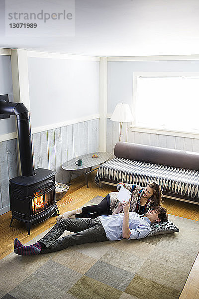 Hochwinkelansicht eines Paares mit einem Tablet-Computer  während es zu Hause auf dem Boden liegt