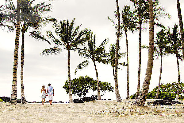 Rückansicht eines Paares  das am Strand auf Sand läuft