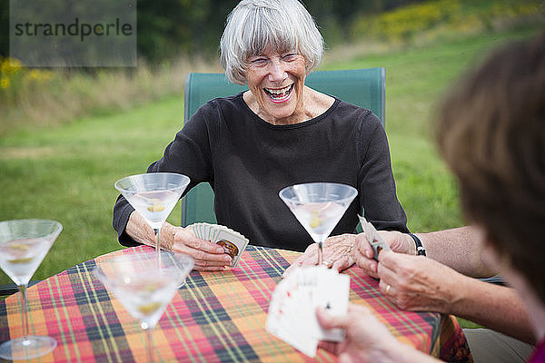 Frau spielt Karten mit Freunden am Tisch auf dem Rasen