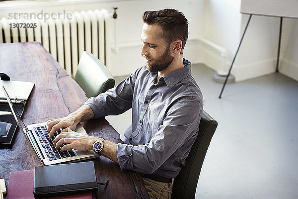 Hochwinkelansicht eines Mannes  der einen Laptop-Computer benutzt  während er im Büro sitzt