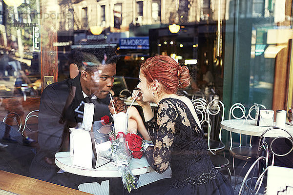 Glückliches Paar trinkt im Restaurant durch Glas gesehen