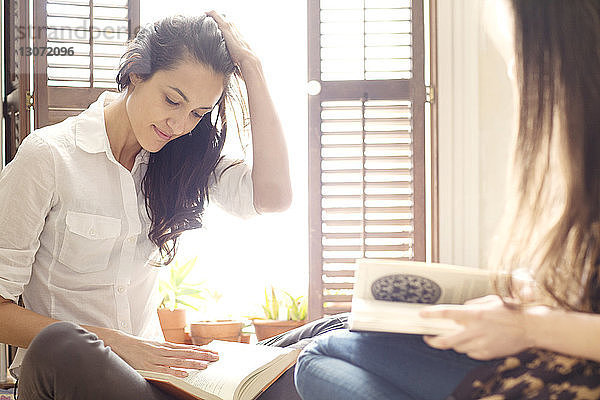 Geschwister lesen Bücher  während sie auf dem Bett sitzen