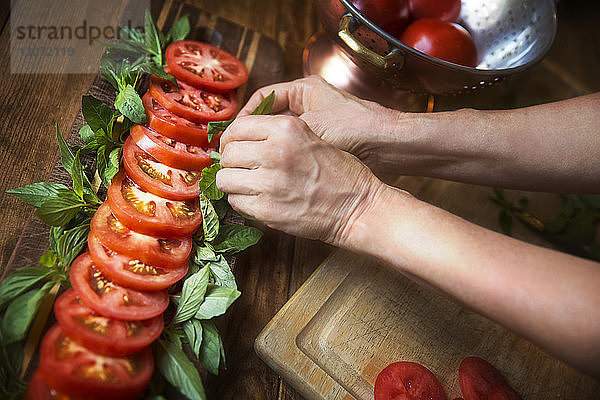 Beschnittenes Bild einer Frau  die bei Tisch Tomatensalat mit Minzblättern garniert
