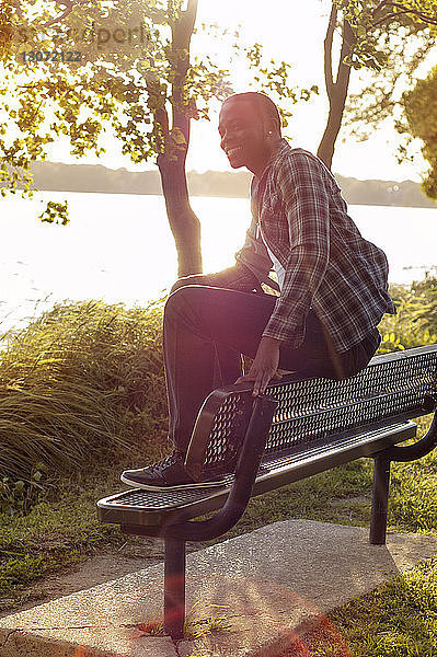Glücklicher Mann sitzt auf Bank im Park am See