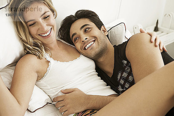Fröhliches Paar liegt zu Hause auf dem Bett