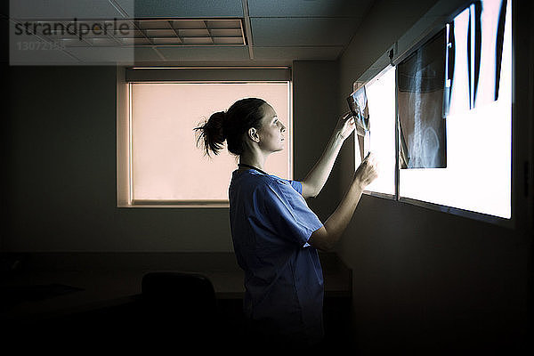 Seitenansicht eines Arztes  der Röntgenbilder auf einem medizinischen Diagnosegerät im Krankenhaus untersucht