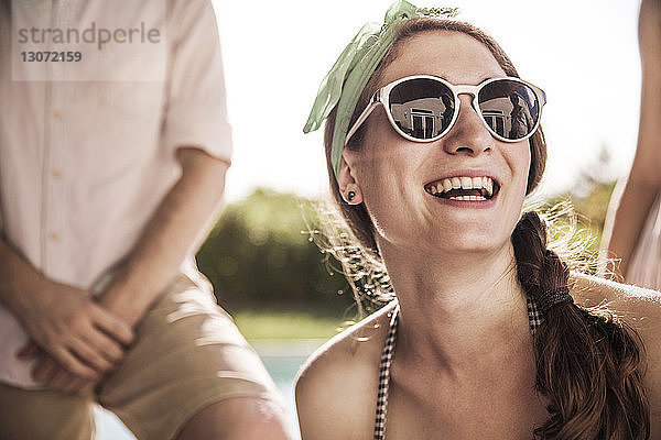 Glückliche Frau mit Sonnenbrille an einem sonnigen Tag im Hinterhof