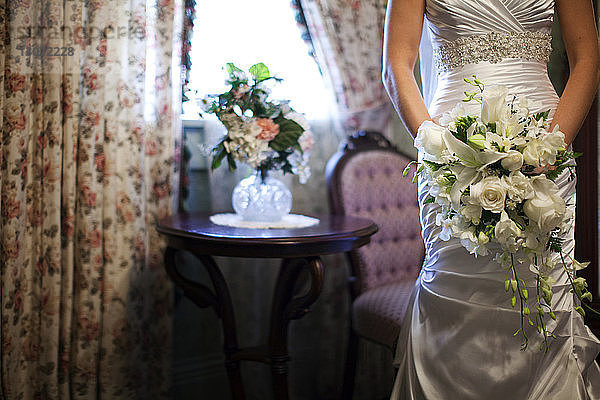 Mittelteil der Braut mit Rosenstrauss  die während des Hochzeitstages zu Hause steht