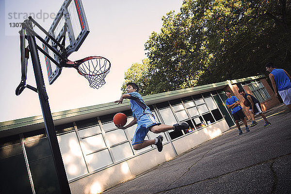 Spieler spielen Basketball auf dem Platz gegen den Himmel