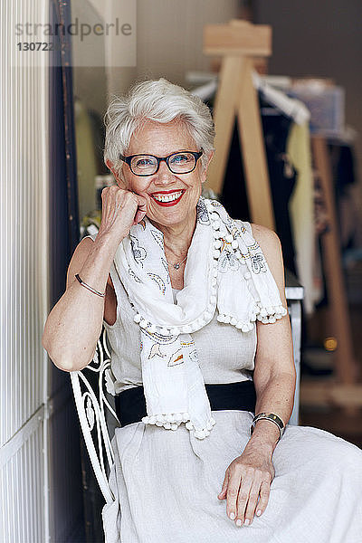 Porträt einer älteren Frau  die auf einem Stuhl vor der Tür sitzt