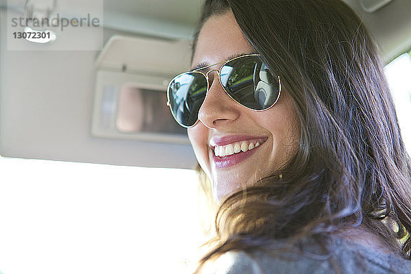 Porträt einer Frau mit Sonnenbrille  die im Auto sitzt