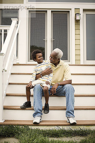 Großvater und Enkel unterhalten sich im Sitzen auf Stufen