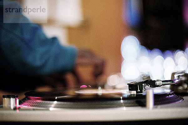 Beschnittenes Bild eines DJs  der Musik am Plattenspieler in einem Nachtclub mixt