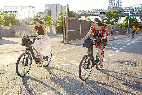 Glückliche Freunde fahren Fahrrad auf der Straße in der Stadt