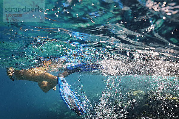 Frau mit Tauchflossen schwimmt unter Wasser