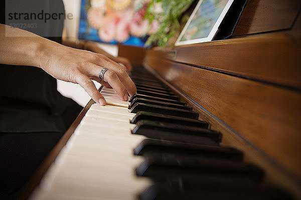 Beschnittenes Bild von Frauenhänden  die zu Hause Klavier spielen