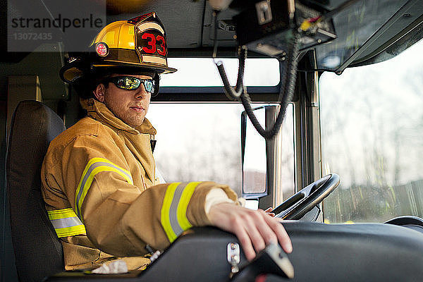 Feuerwehrmann mit Sonnenbrille im Feuerwehrauto sitzend