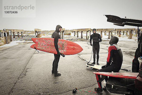 Freunde in Neoprenanzügen bereiten sich auf das Surfen vor