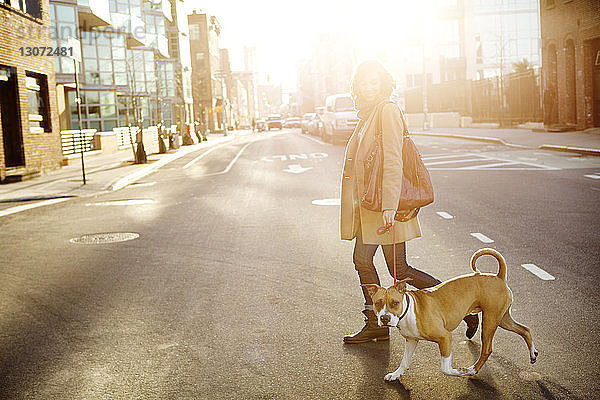 Seitenansicht einer Frau mit Hund beim Überqueren einer Straße in der Stadt