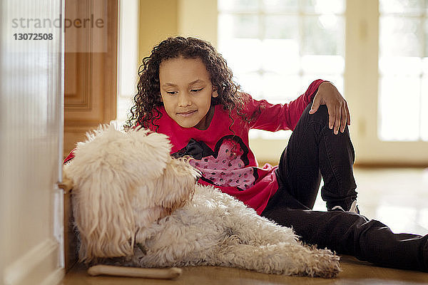 Mädchen sieht Hund an  während sie auf dem Boden sitzt