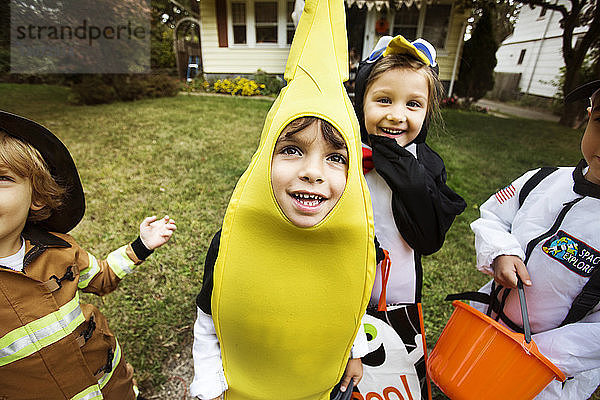 Fröhliche Kinder in Halloween-Kostümen  die sich im Hof beim Streicheln oder Behandeln amüsieren