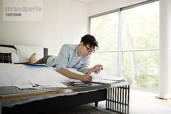 Mann hört Musik  während er zu Hause im Schlafzimmer an einem Dokument arbeitet