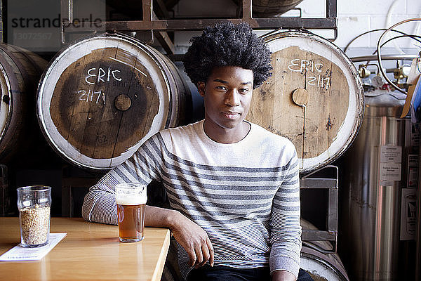 Porträt eines Mannes  der in einer Brauerei Bier trinkt  während er am Tisch sitzt