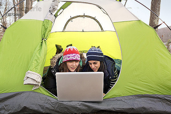 Freunde benutzen Laptop-Computer  während sie im Zelt liegen