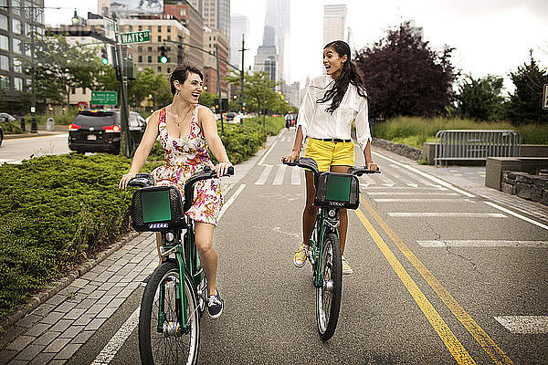 Fröhliche Freunde fahren Fahrrad auf der Straße