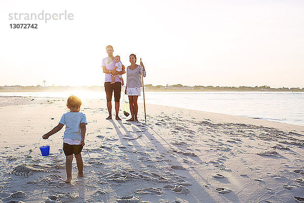 Familie in voller Länge am Strand gegen den Himmel an einem sonnigen Tag