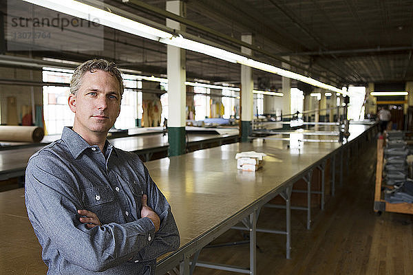 Porträt eines Geschäftsmannes  der in der Fabrik am Tisch steht