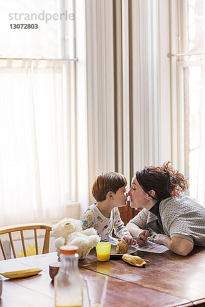 Mutter und Sohn reiben sich die Nase  während sie zu Hause am Tisch sitzen