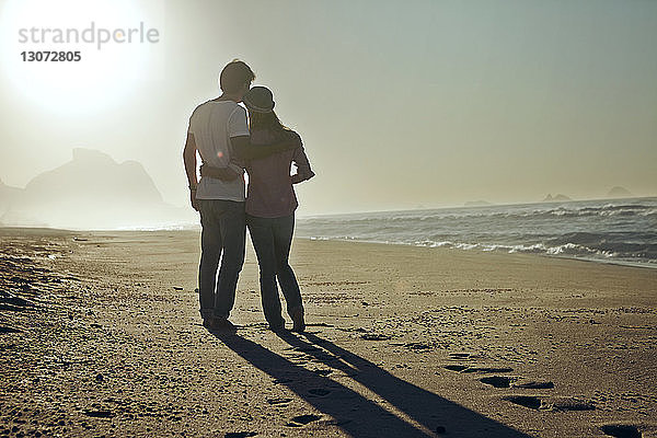 Rückansicht eines am Strand stehenden Paares bei klarem Himmel