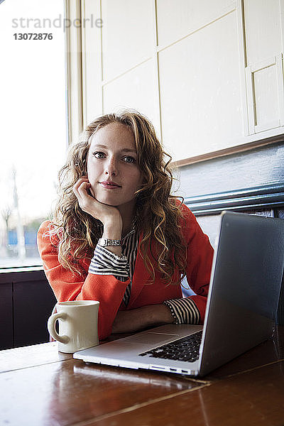 Porträt einer Frau mit Hand am Kinn im Café sitzend