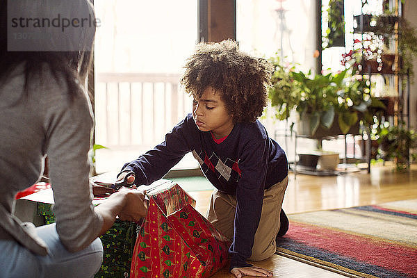 Mutter und Sohn packen zu Hause Weihnachtsgeschenke ein