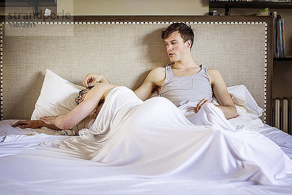 Schwuler Mann sieht Freund an  während er zu Hause im Bett liegt