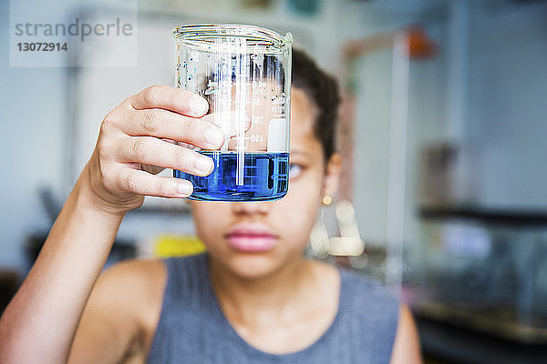 Schüler untersucht Chemikalie im Becherglas im High-School-Labor