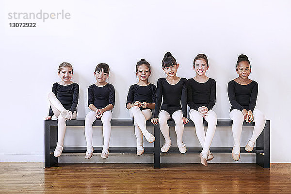 Porträt von selbstbewussten Ballerinen auf einer Bank im Ballettstudio