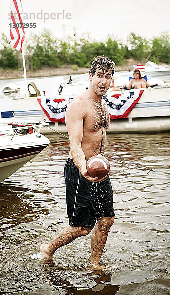 Porträt eines Mannes  der einen Fussball hält  während er im Wasser geht