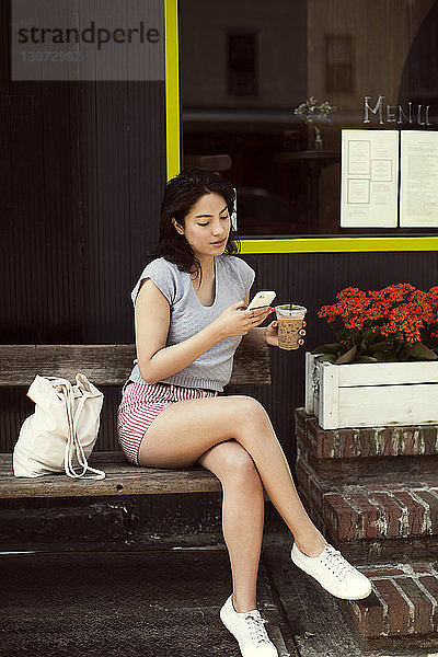 Frau telefoniert beim Kaffeetrinken in einem Straßencafé in der Stadt