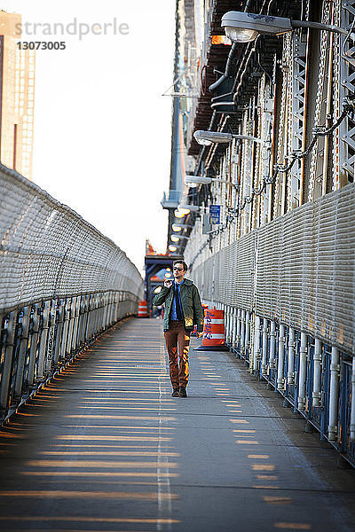 Mann schaut weg  während er auf dem Fußgängerweg der Manhattan Bridge geht